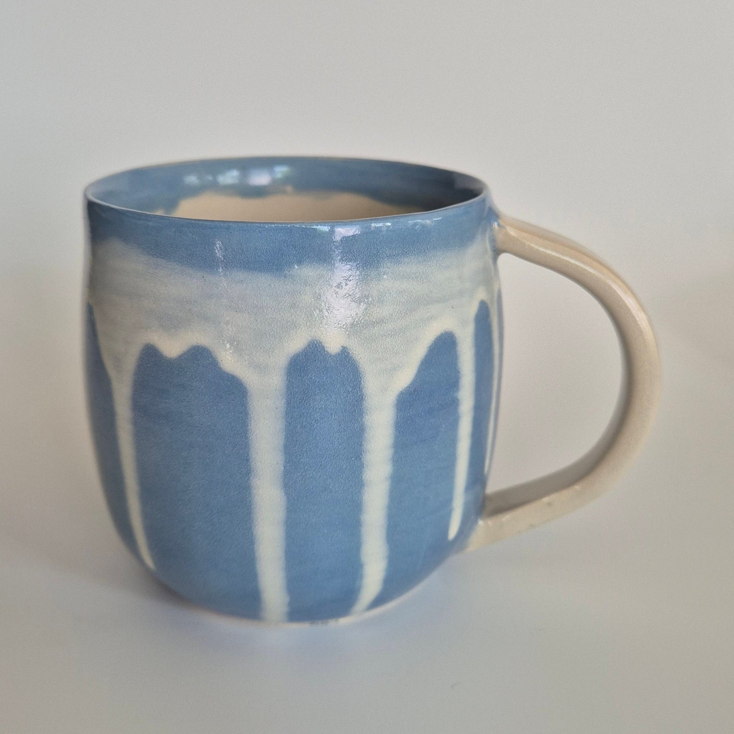 Ceramic mug with blue and white abstract design on a plain background