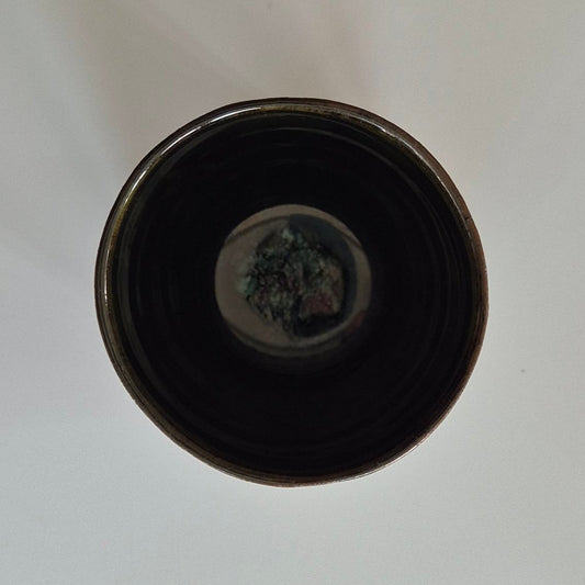 Inside of dark green ceramic pencil pot. On a light background