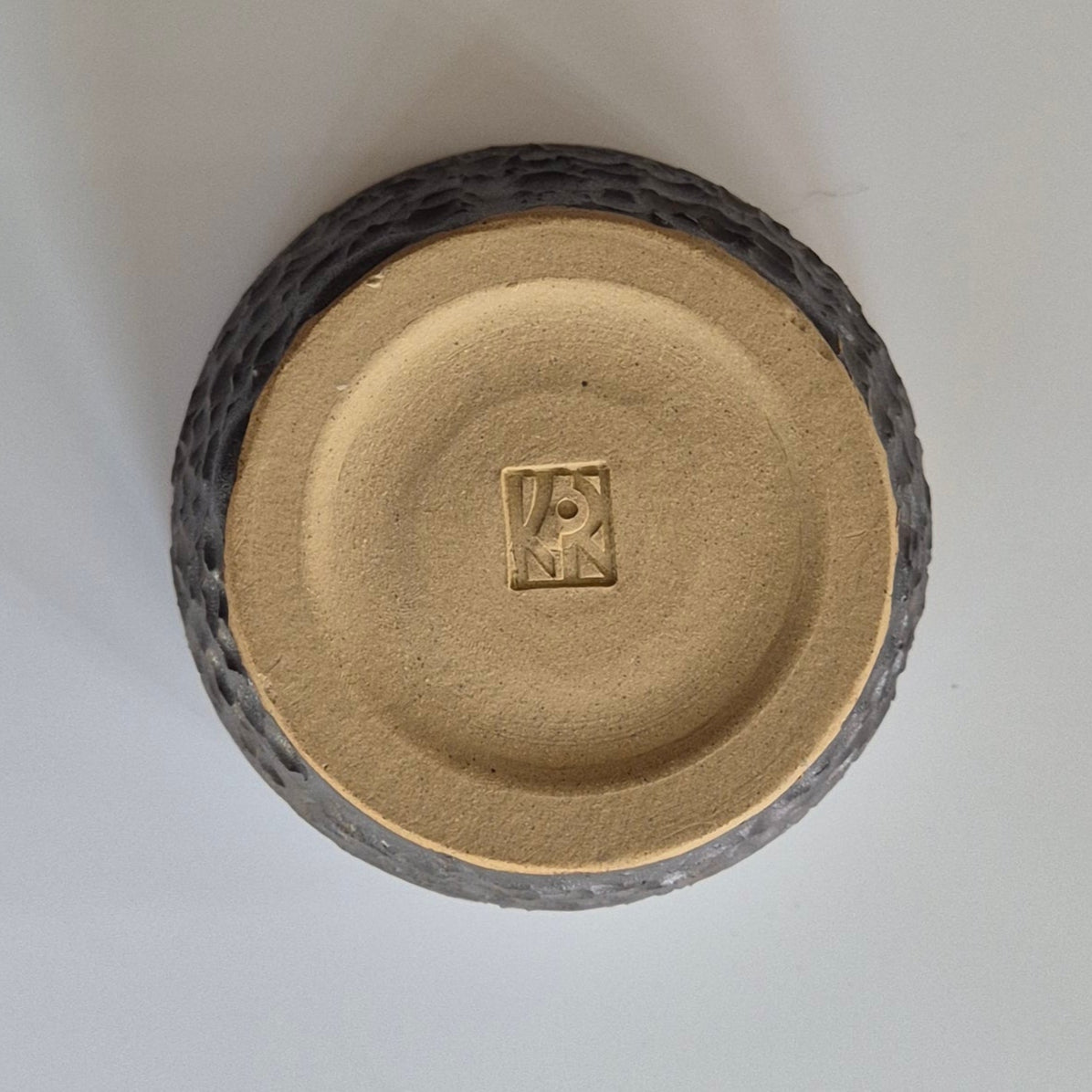 Round ceramic object with a textured surface on a white background