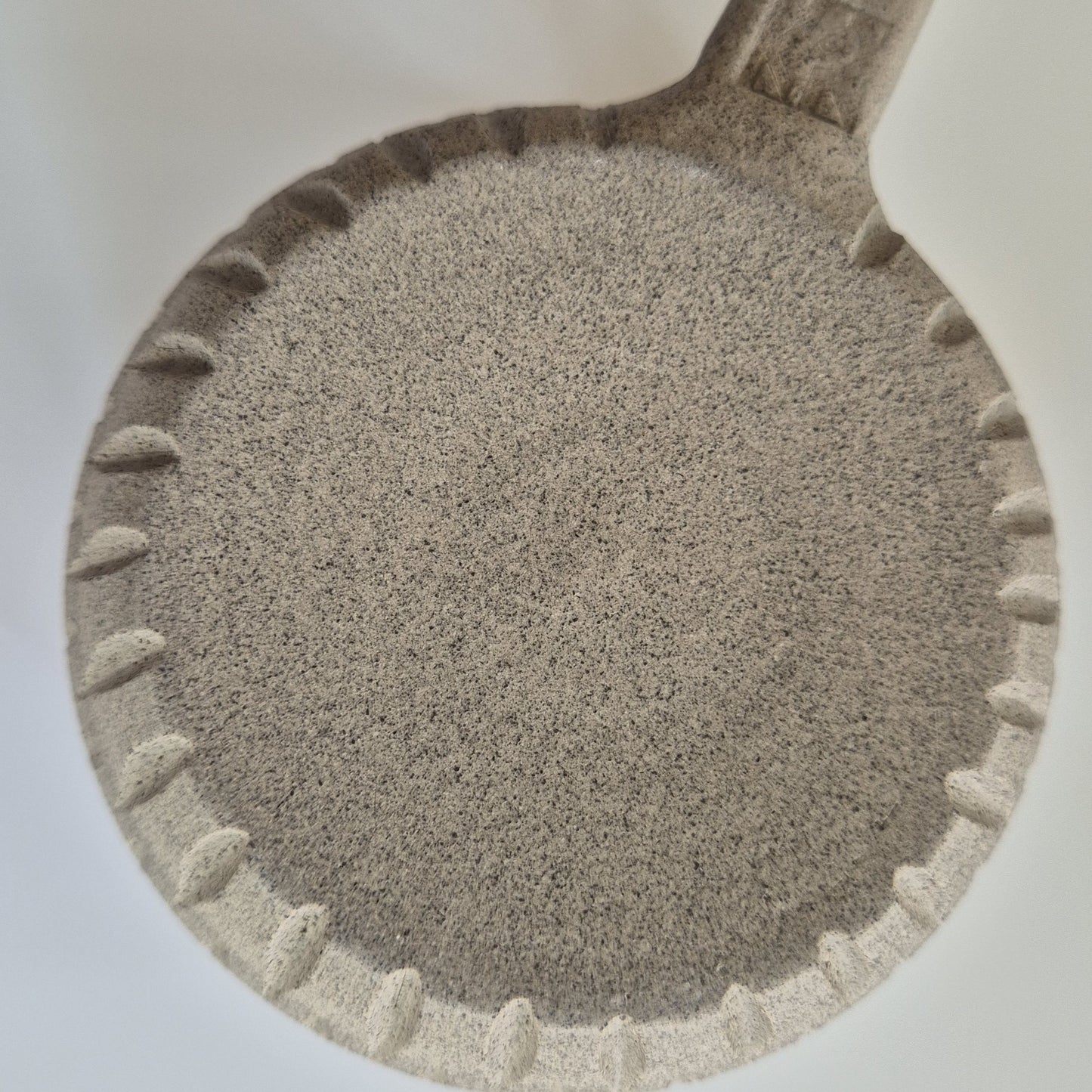 Base of a ceramic mug showing carved detail on a light background