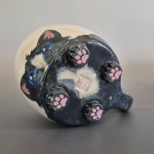 Ceramic cat mug showing the base and 4 paws with toe beans on a gray background
