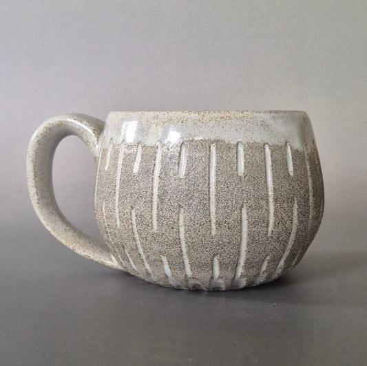 Ceramic mug with textured surface and handle on a gray background