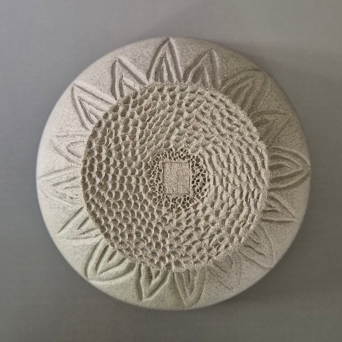 Base of round bowl with sunflower pattern on a gray background