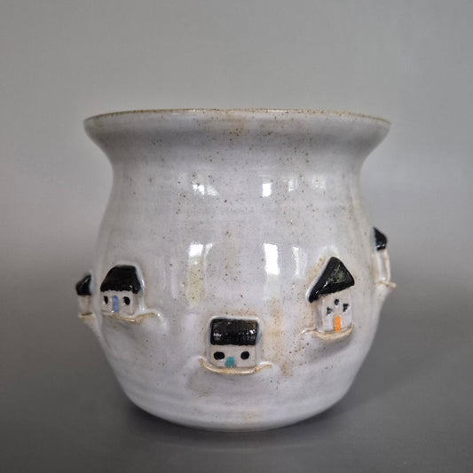 Ceramic pot with small houses on a gray background
