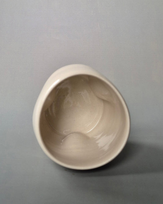 Top view of a small white stoneware pot indented to embrace 3 tiny cottages. On a grey background