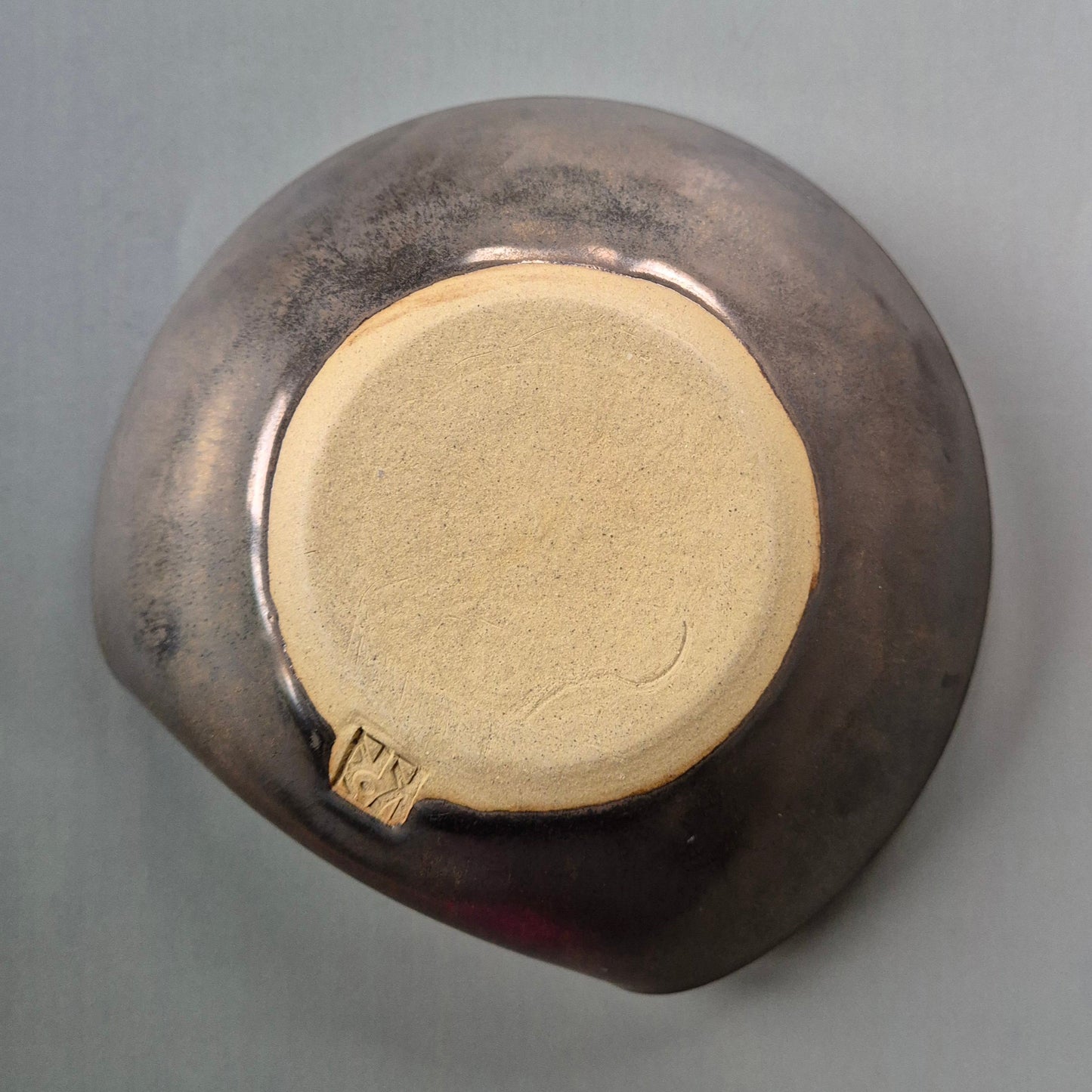 Base of a handmade stoneware trinket dish showing the maker’s mark