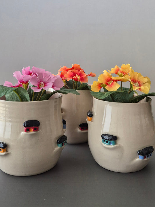 Three ceramic planters with tiny sculptural houses on a gray background