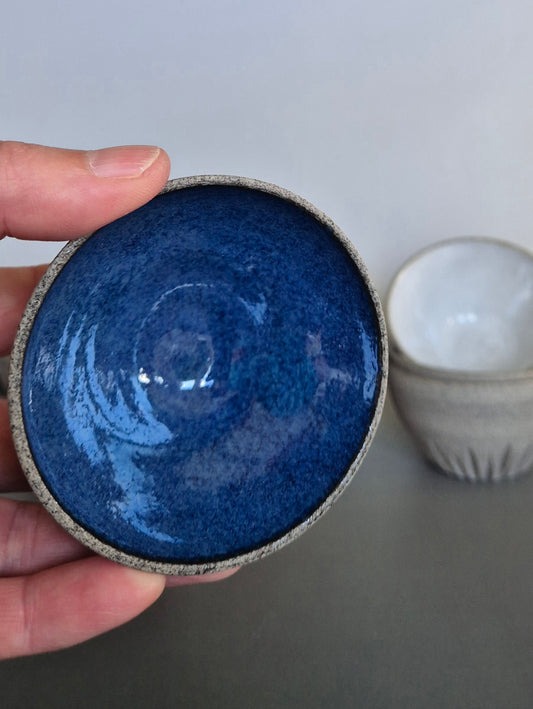 Hand holding a blue ceramic bowl with a white background