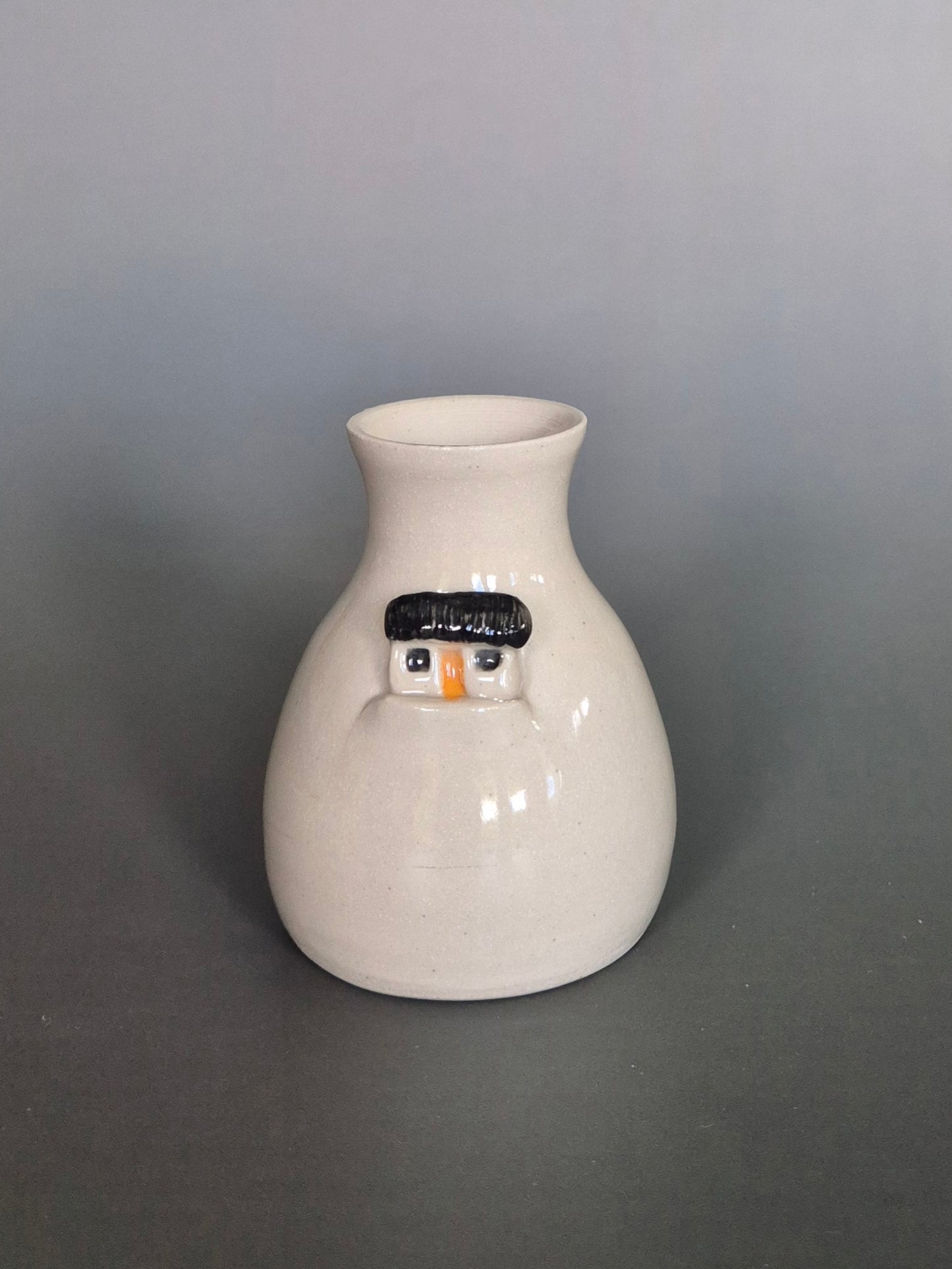 White ceramic vase with a house design on a gray background
