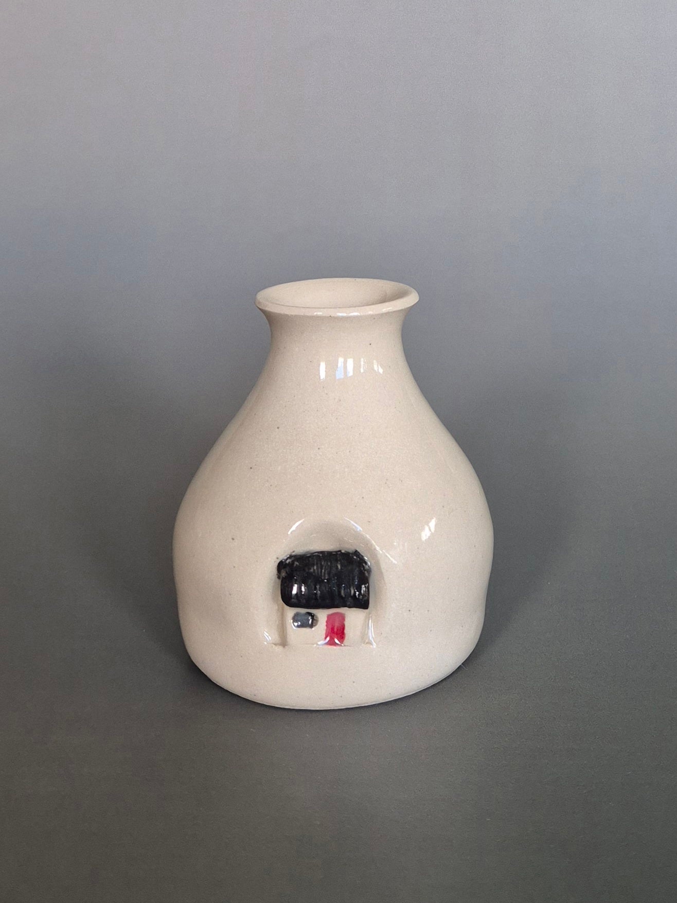 Small white ceramic bottle or bud vase. On a plain background