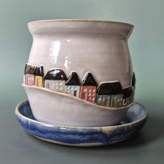 Ceramic planter with miniature houses on a gray background