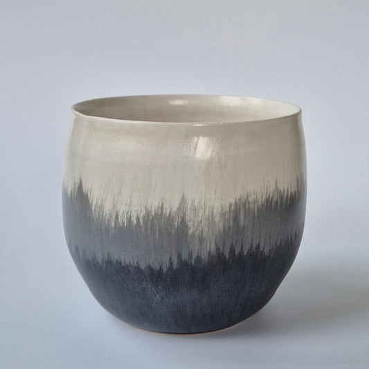 Ceramic planter with gradient gray and black design on a light gray background