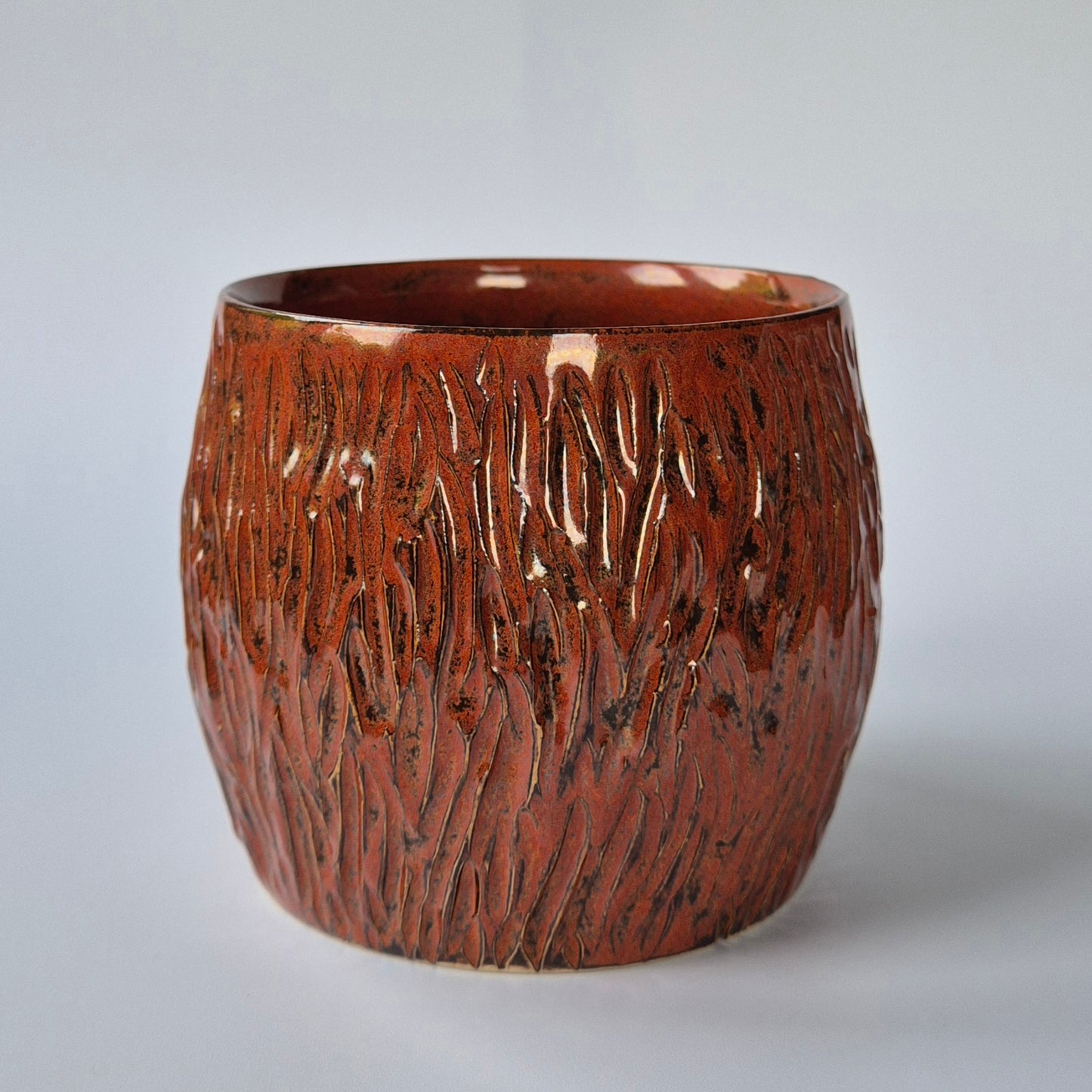 Brown ceramic pot with textured surface on a light gray background