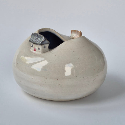 Tiny house ceramic bud vase on a plain grey background