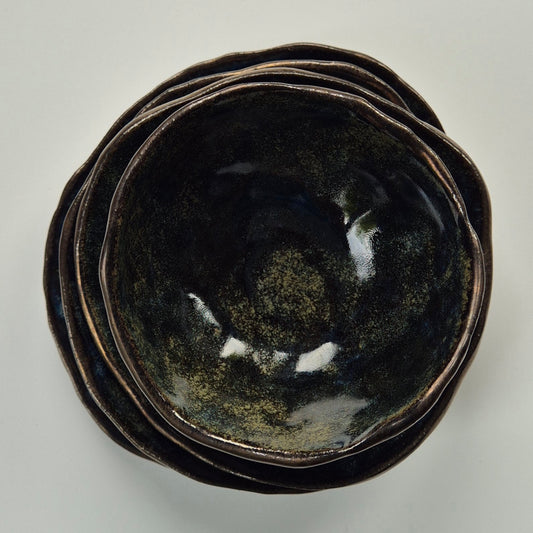 Stack of black ceramic bowls on a light gray background