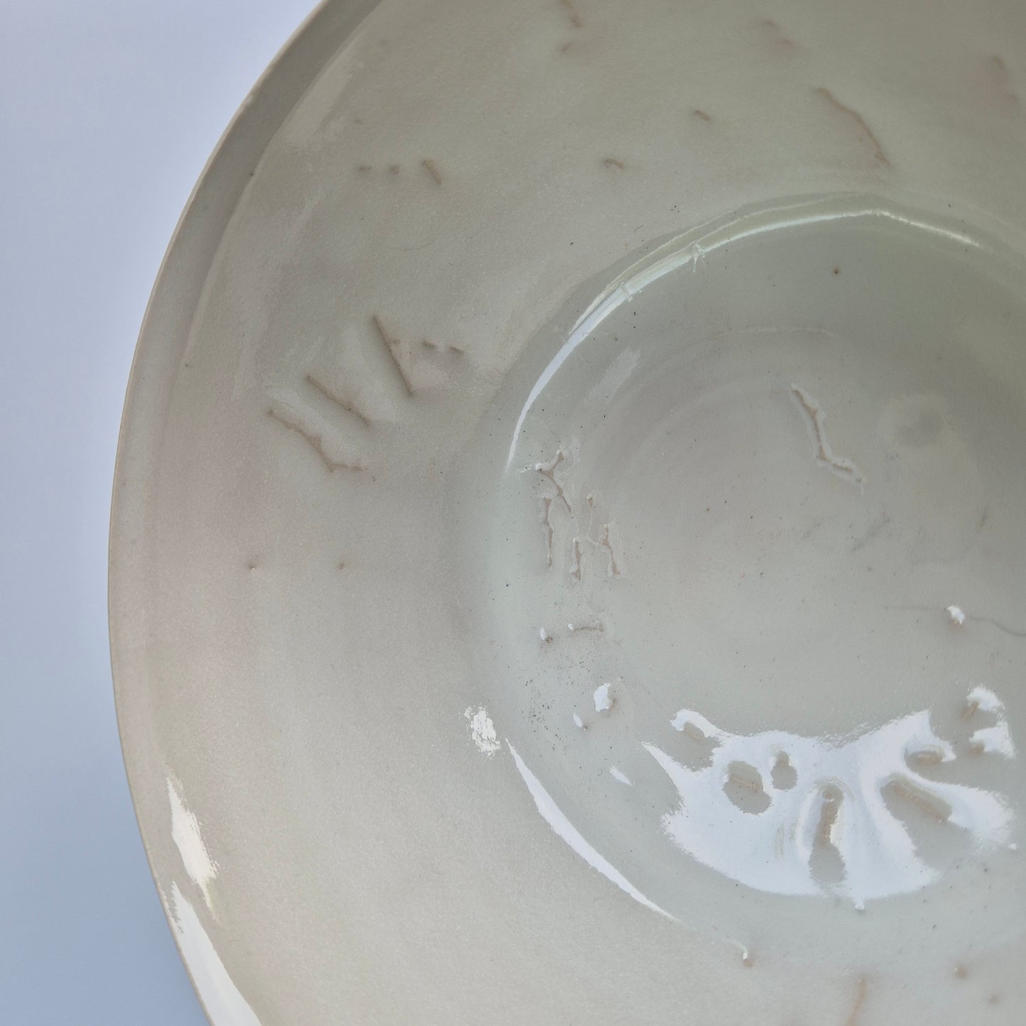 Close-up of a ceramic bowl with visible texture and imperfections on a white background