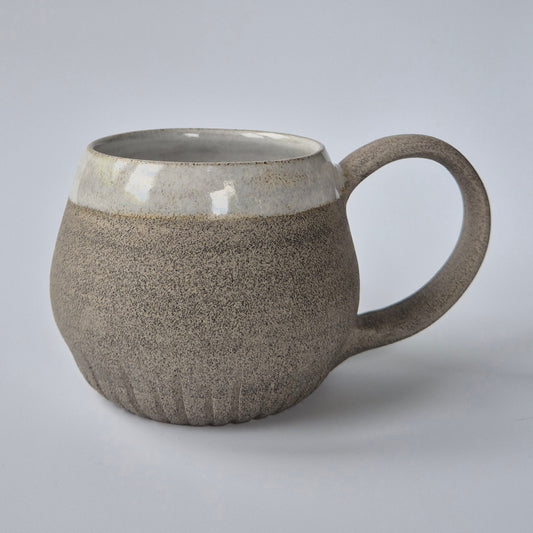 Stoneware mug with a textured body and smooth top on a light gray background