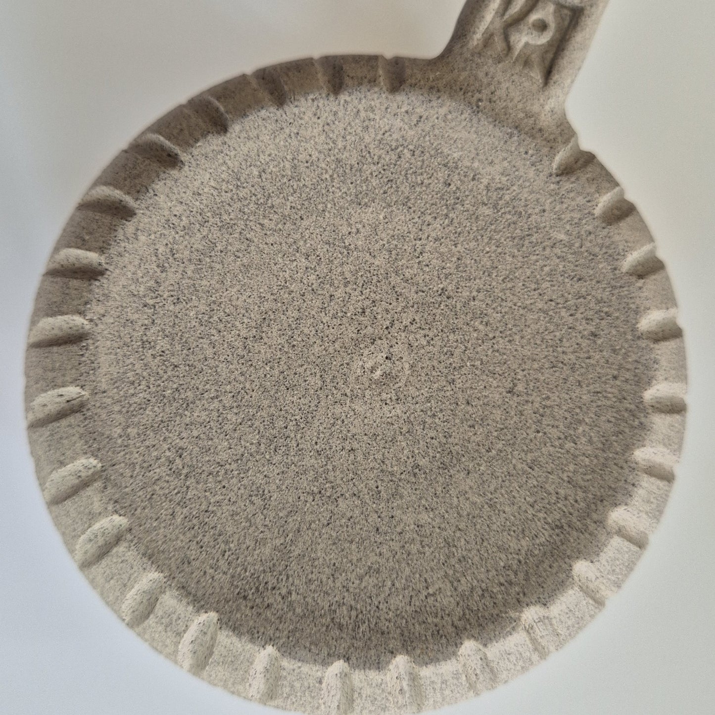 Base of a ceramic mug showing carved surface detail on a white background