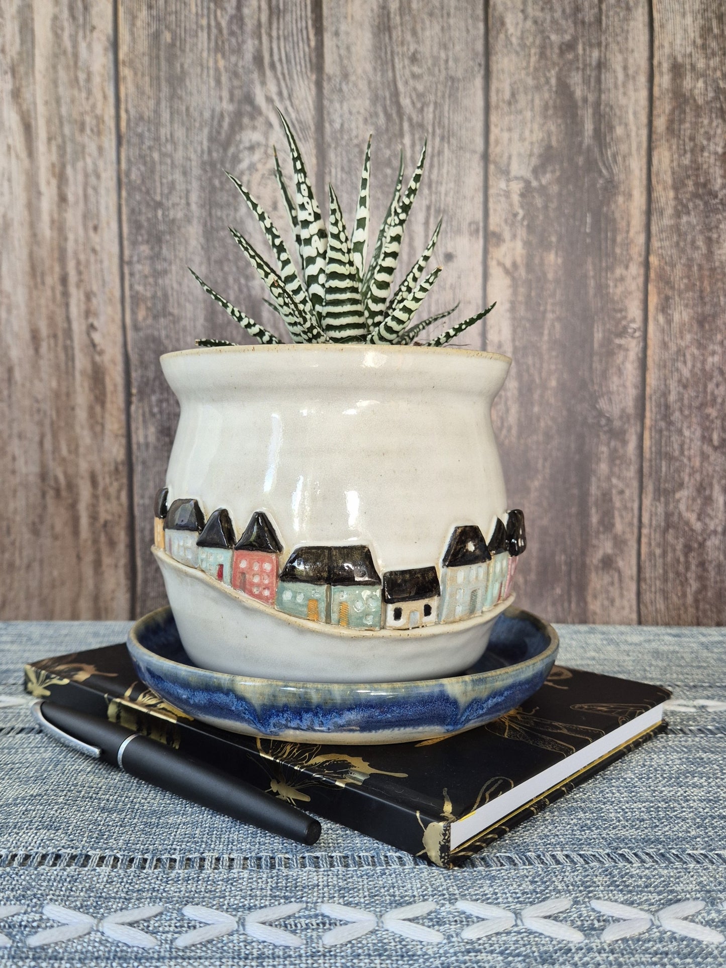 Ceramic pot with decorative design on a notebook against a wooden background
