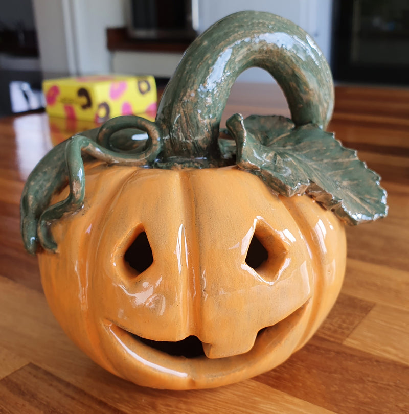 Ceramic pumpkin with a face on a wooden surface