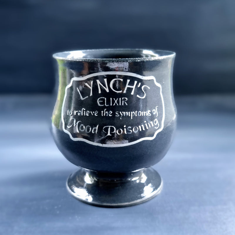 Black ceramic goblet with text on a dark background