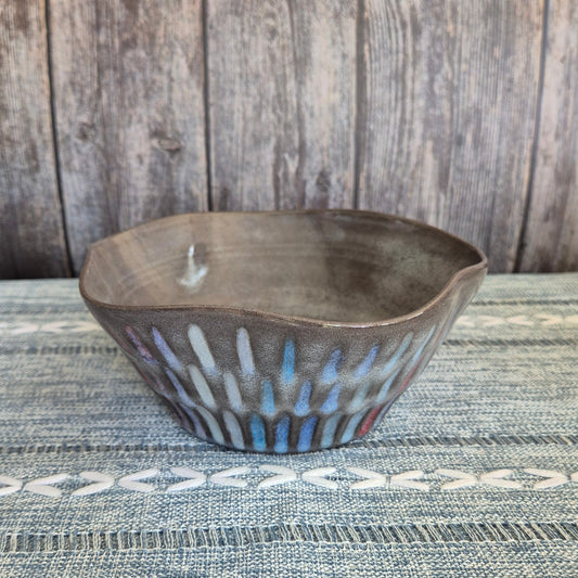Decorative ceramic bowl on a textured surface with wooden background