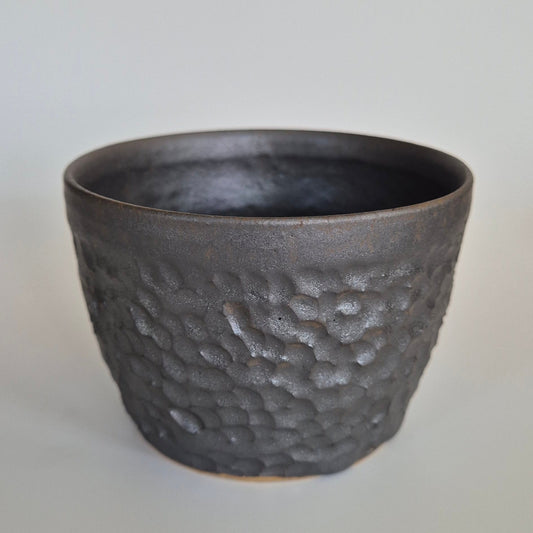 Textured black ceramic cup on a light gray background
