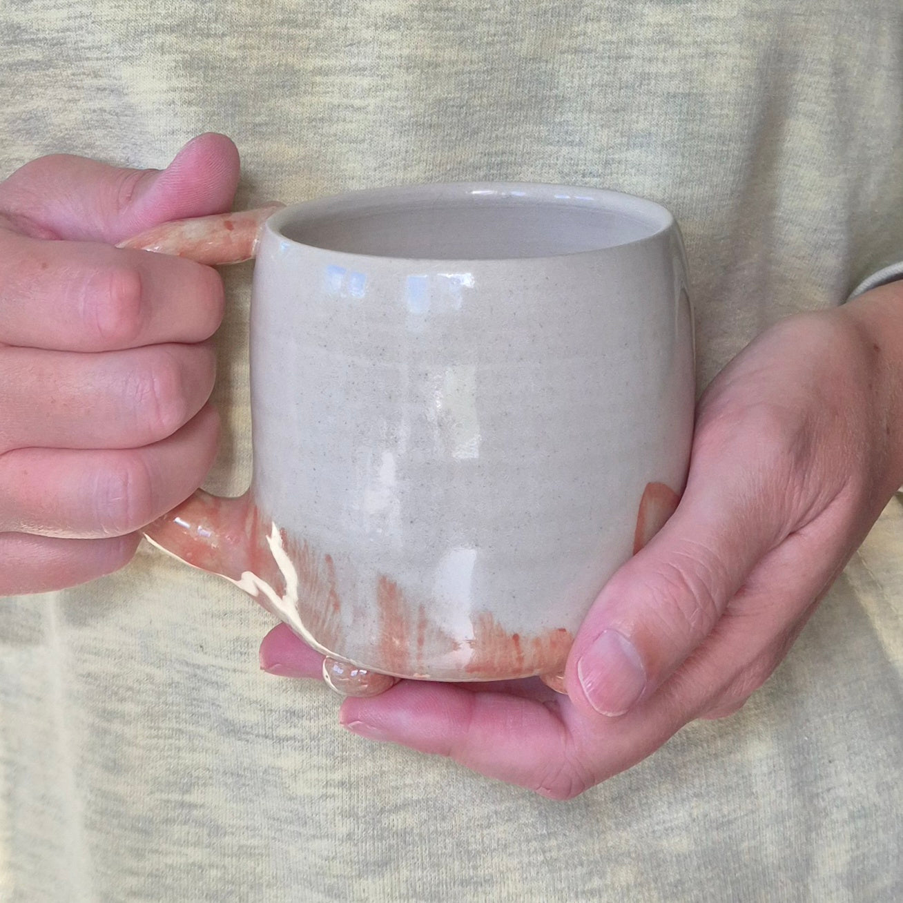 Person holding a white ceramic mug with a subtle gradient effect.
