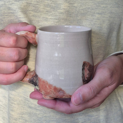 Person holding a ceramic mug with a unique glaze pattern