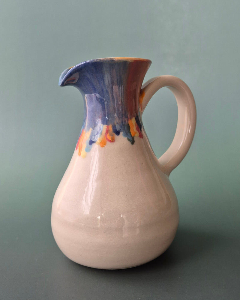Ceramic pitcher with a handle on a plain background