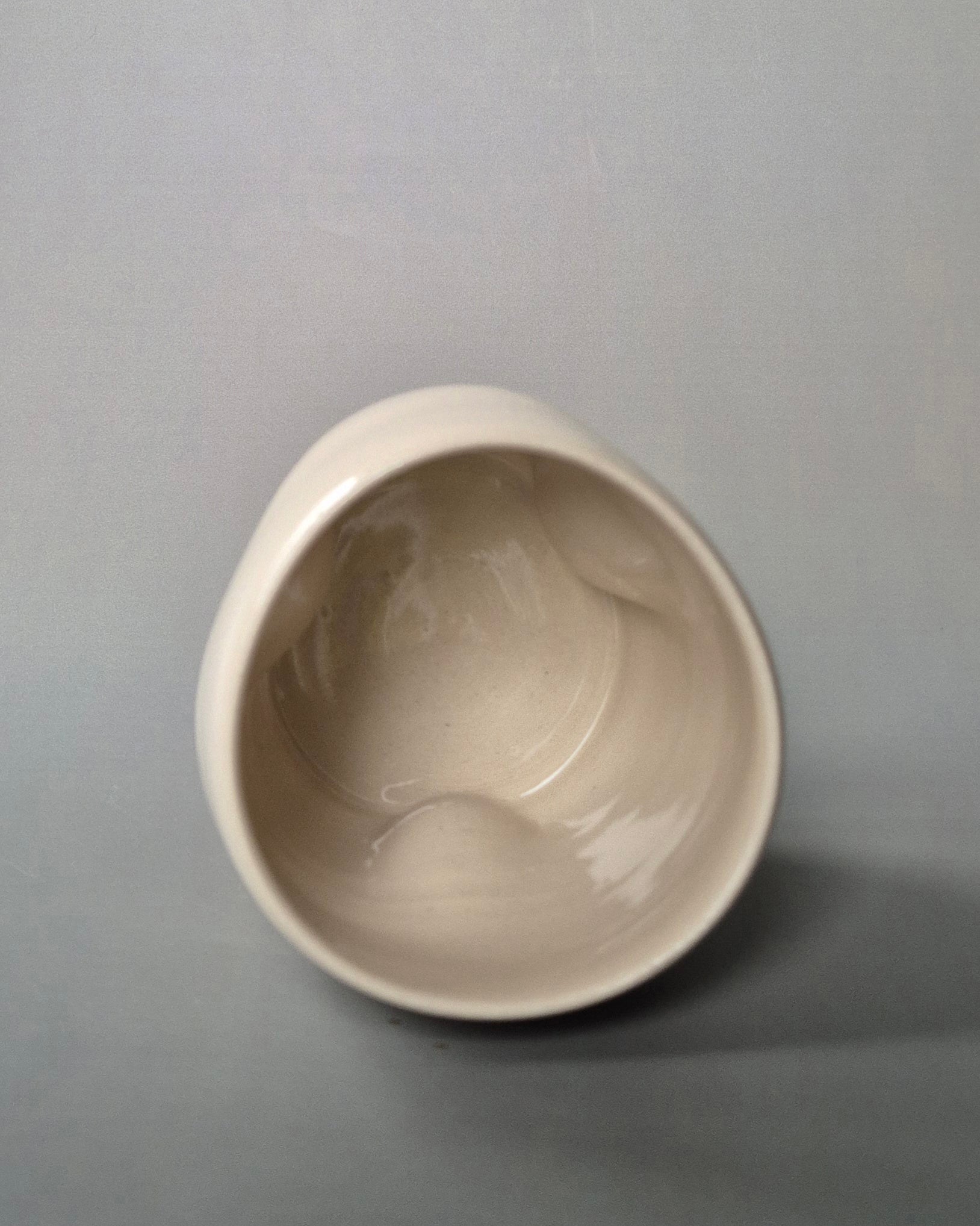 Top view of a small white stoneware pot indented to embrace 3 tiny cottages. On a grey background