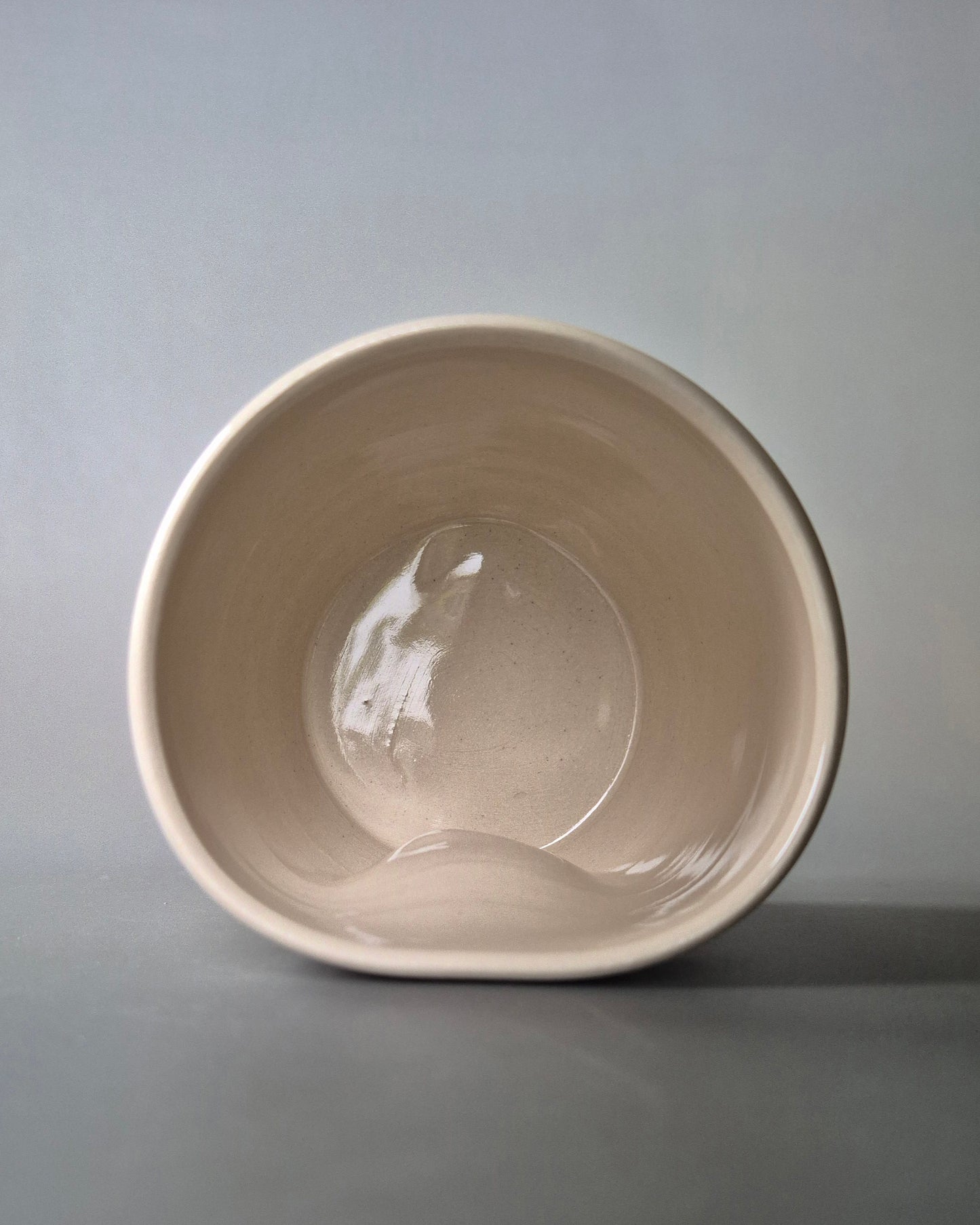 Photo showing the inside of a small white stoneware pot. On a grey background.