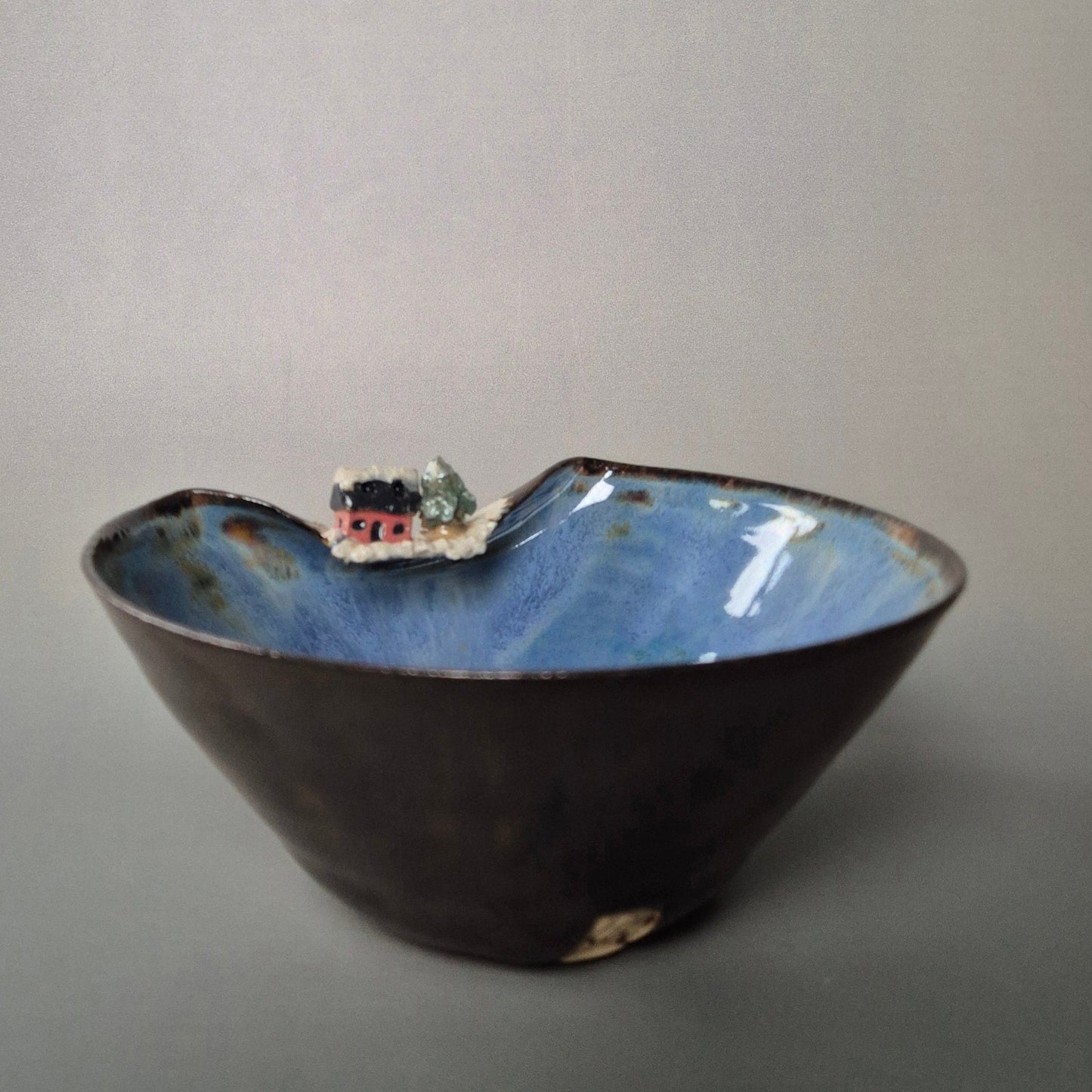 Ceramic bowl with a small landscape model on a gray background
