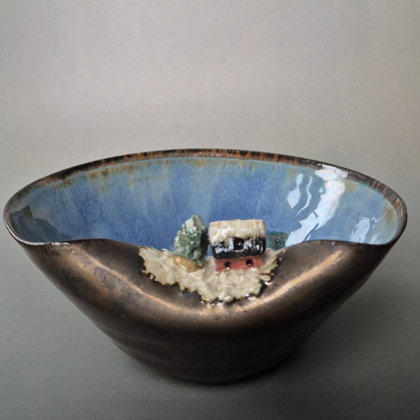 Ceramic bowl with a textured surface and embedded decorative elements on a plain background