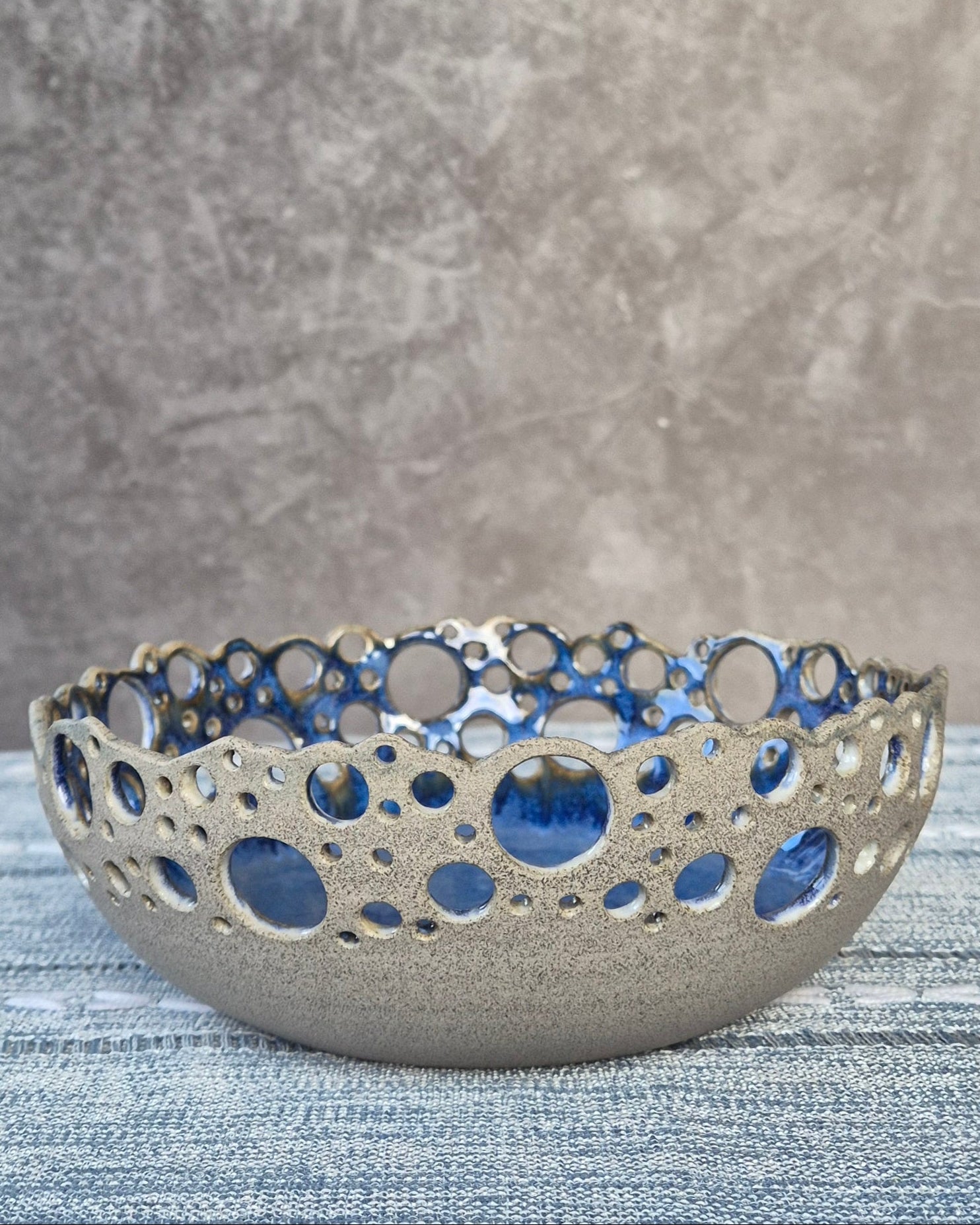 Decorative ceramic bowl with blue accents on a textured surface