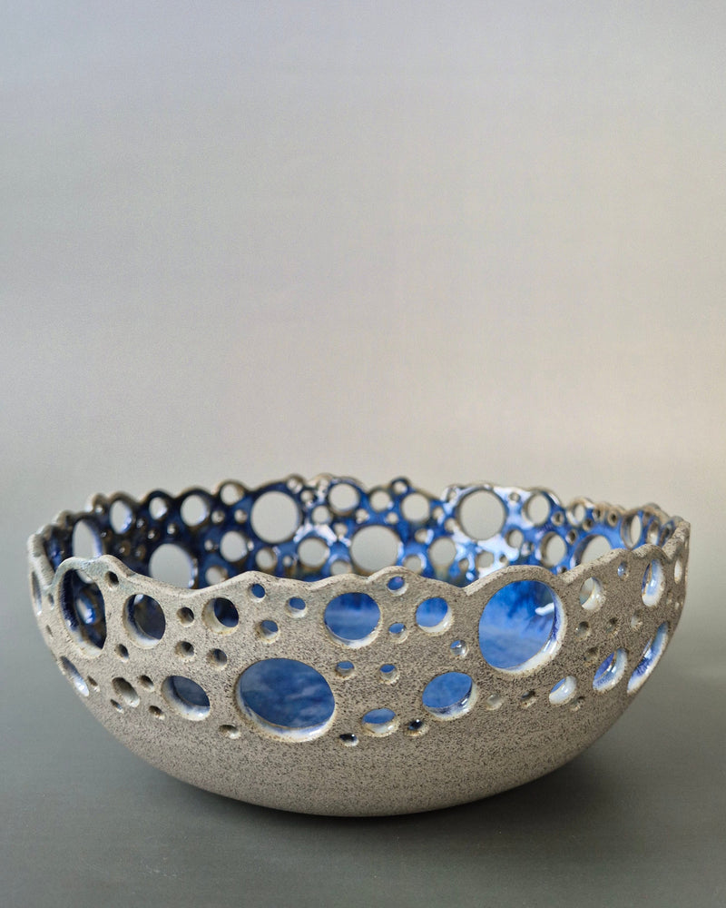Ceramic bowl with blue interior and textured exterior on a gray background