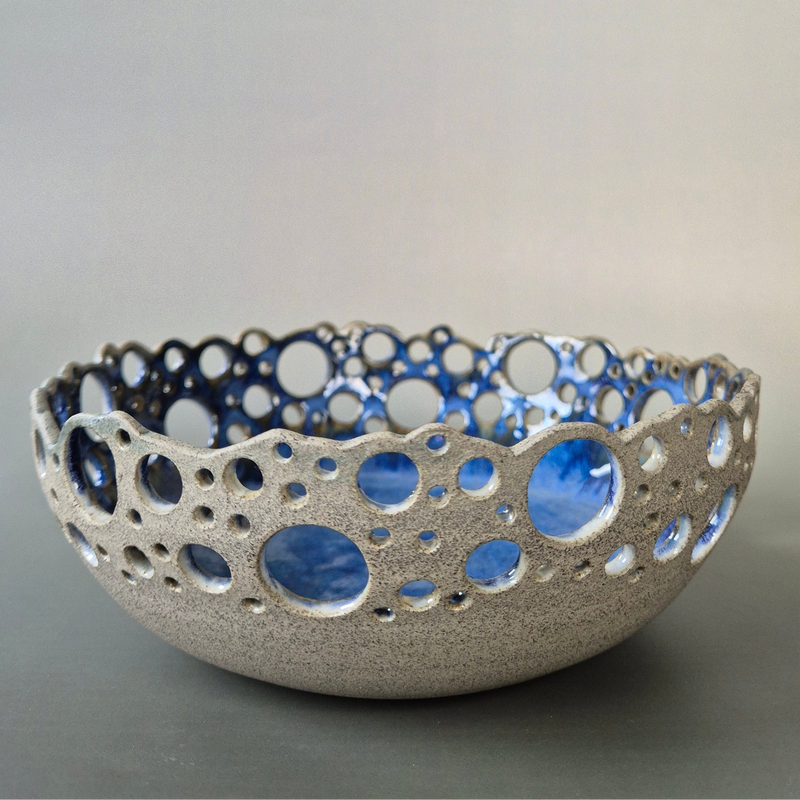 Ceramic bowl with textured surface and blue interior on a gray background