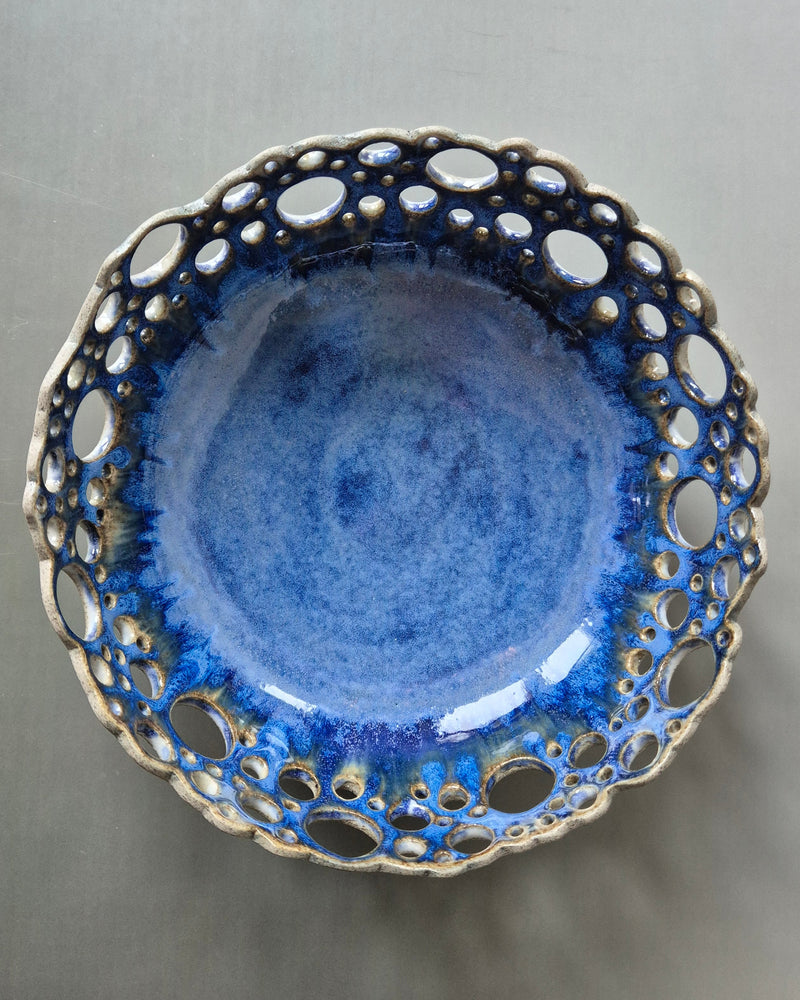Blue ceramic bowl with decorative rim on a gray background