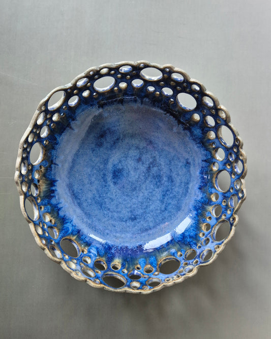Ceramic bowl with blue glaze and unglazed rim on a gray background