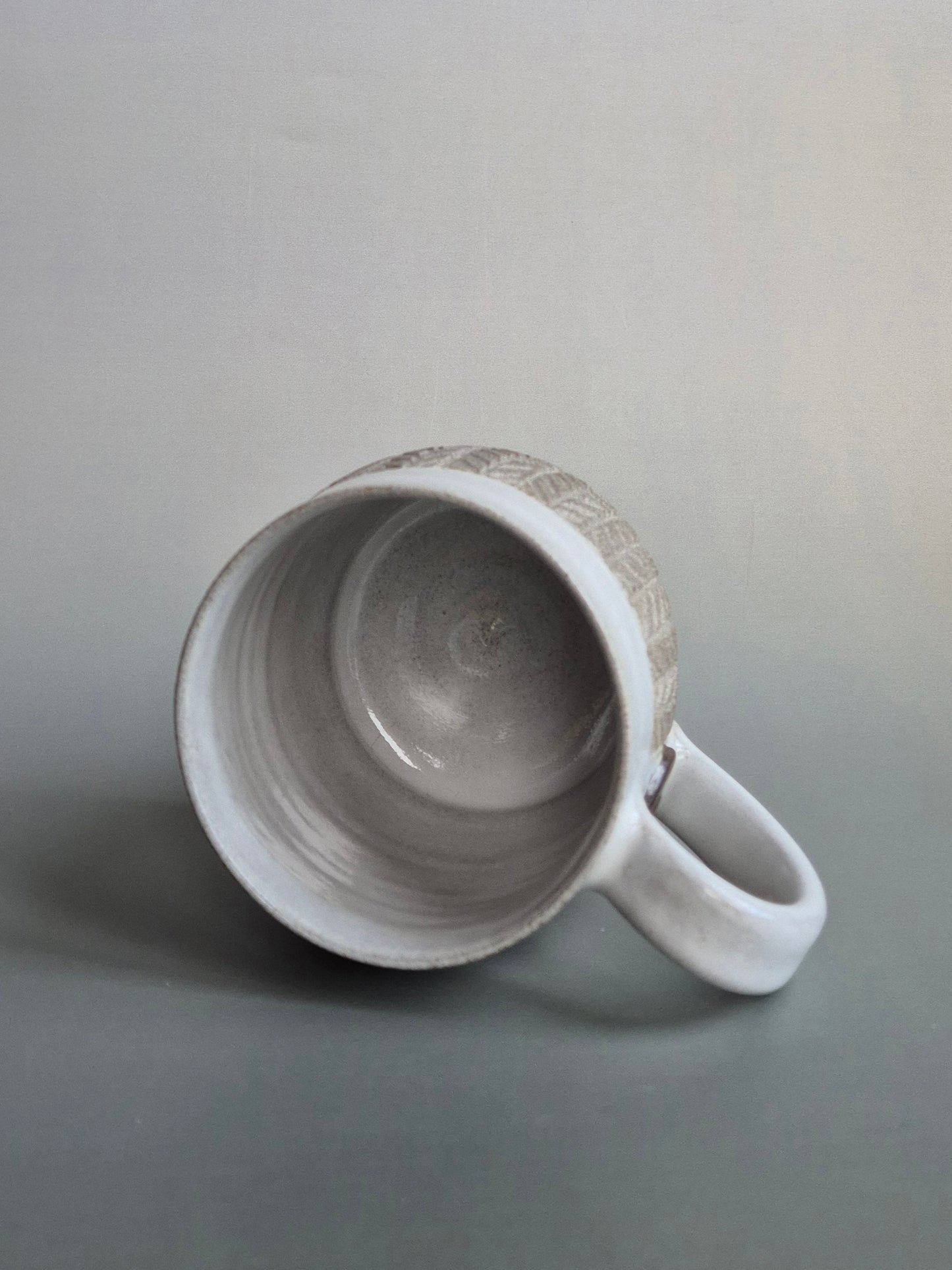 White ceramic mug with textured interior on a gray background