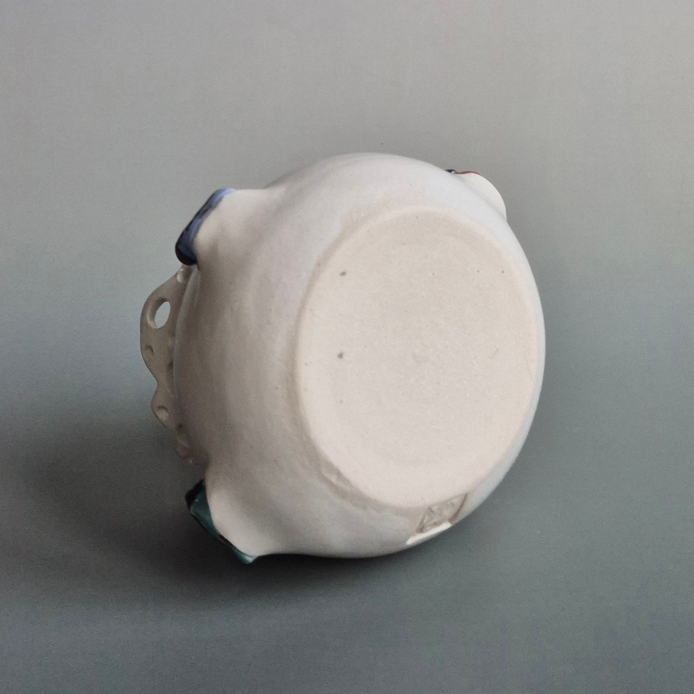 Base of a ceramic candle jar on a gray background