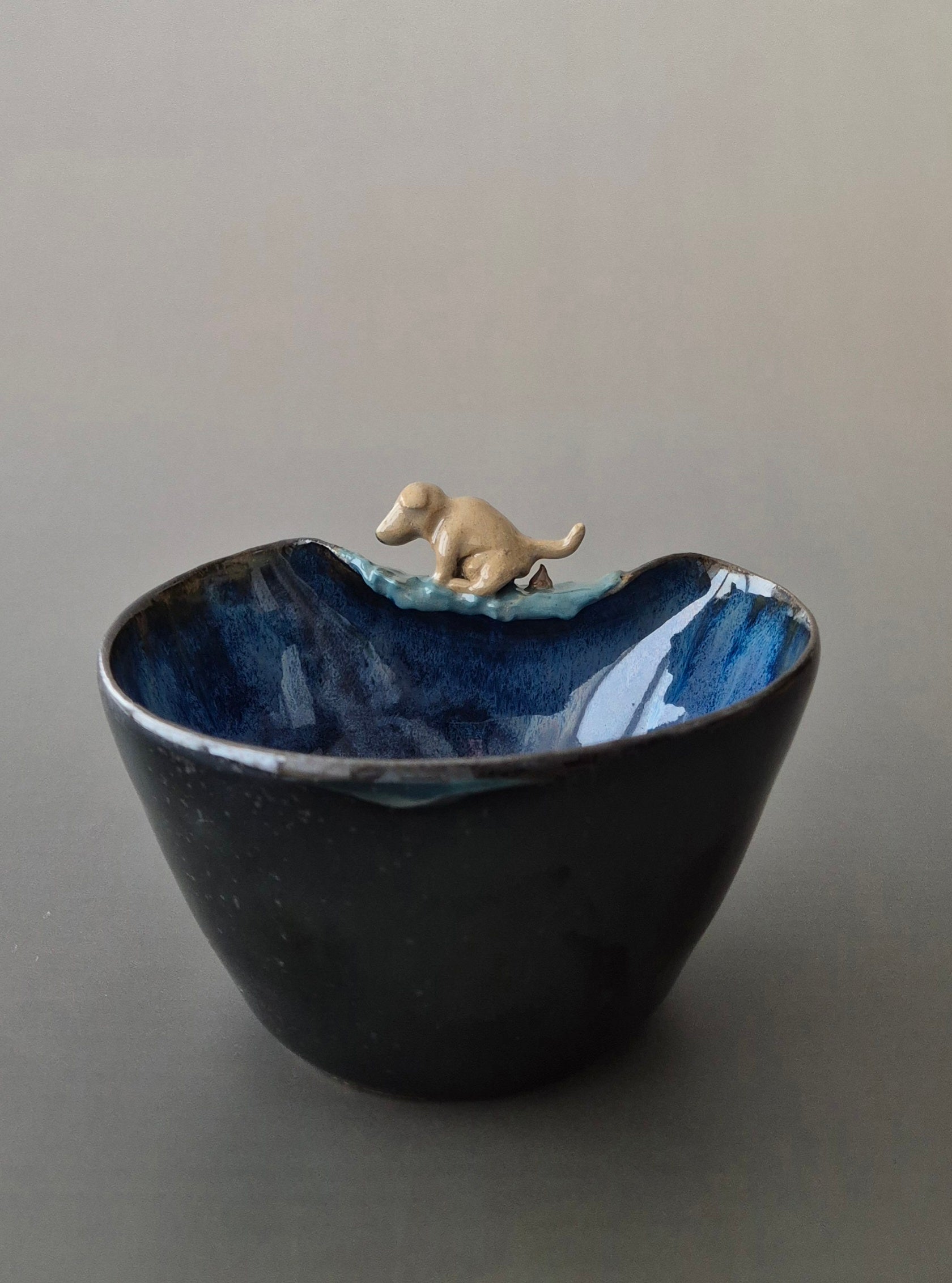 Ceramic bowl with a small dog figurine on a gray background