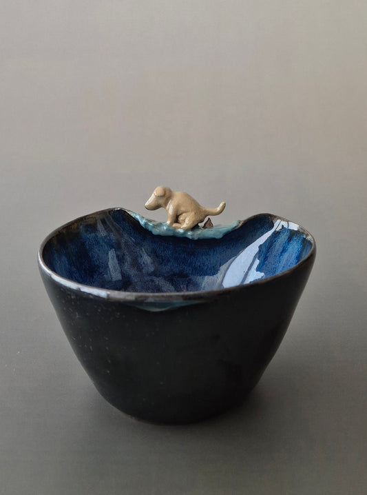 Ceramic bowl with a small dog figurine on a gray background