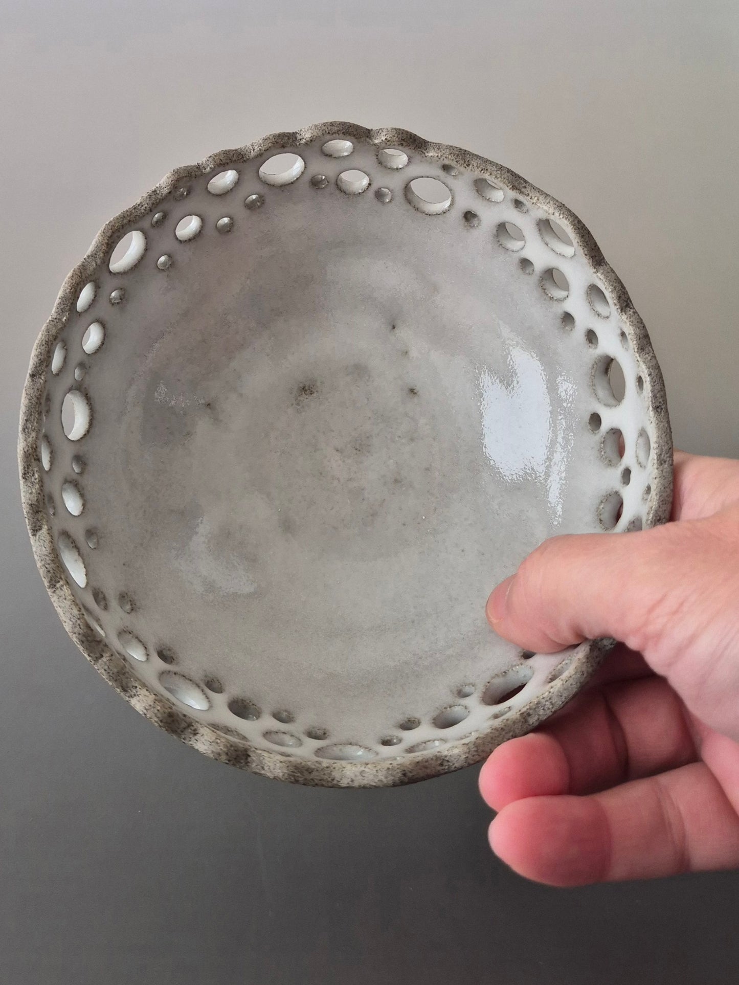Hand holding a textured ceramic bowl against a plain background