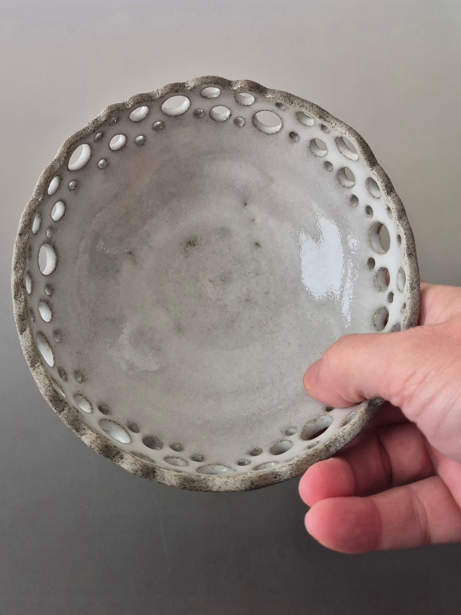 Hand holding a textured ceramic bowl against a plain background