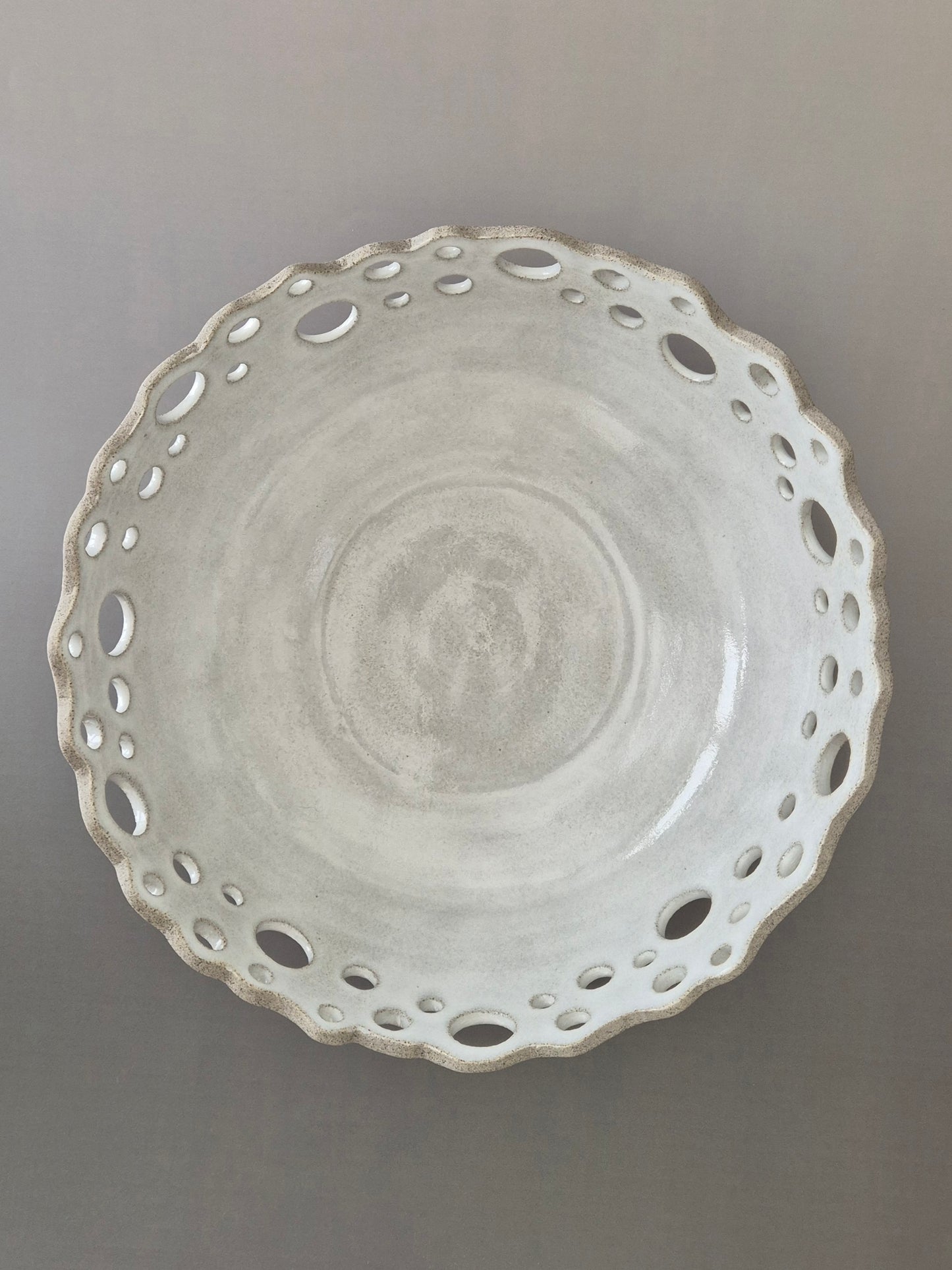 Decorative ceramic bowl with cut-out design on a gray background