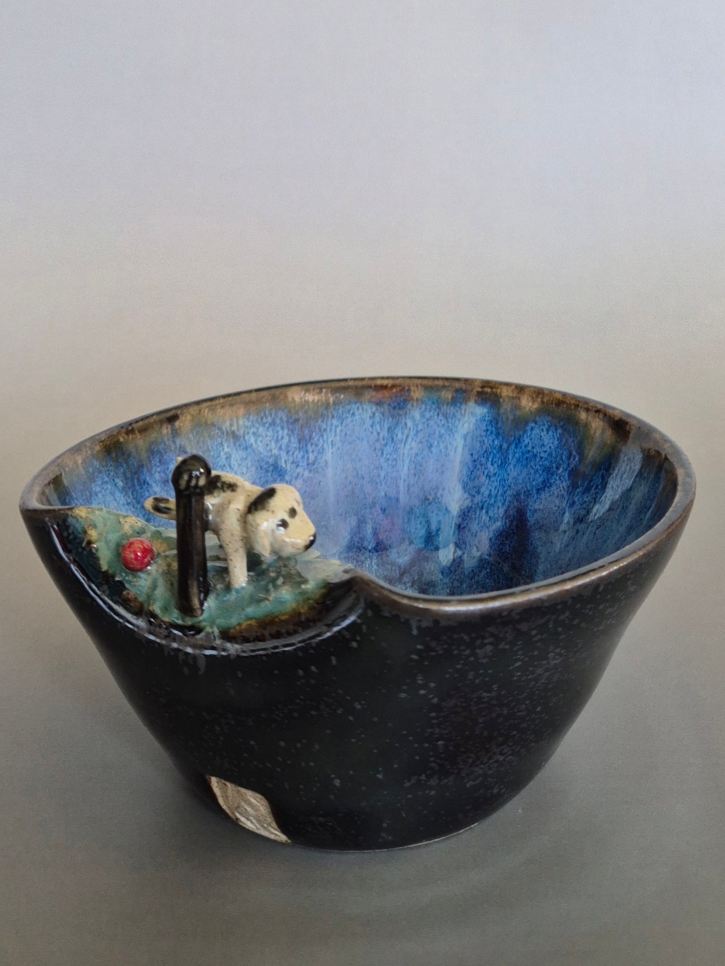 Ceramic bowl with a miniature scene of a dog by a pond on a plain background