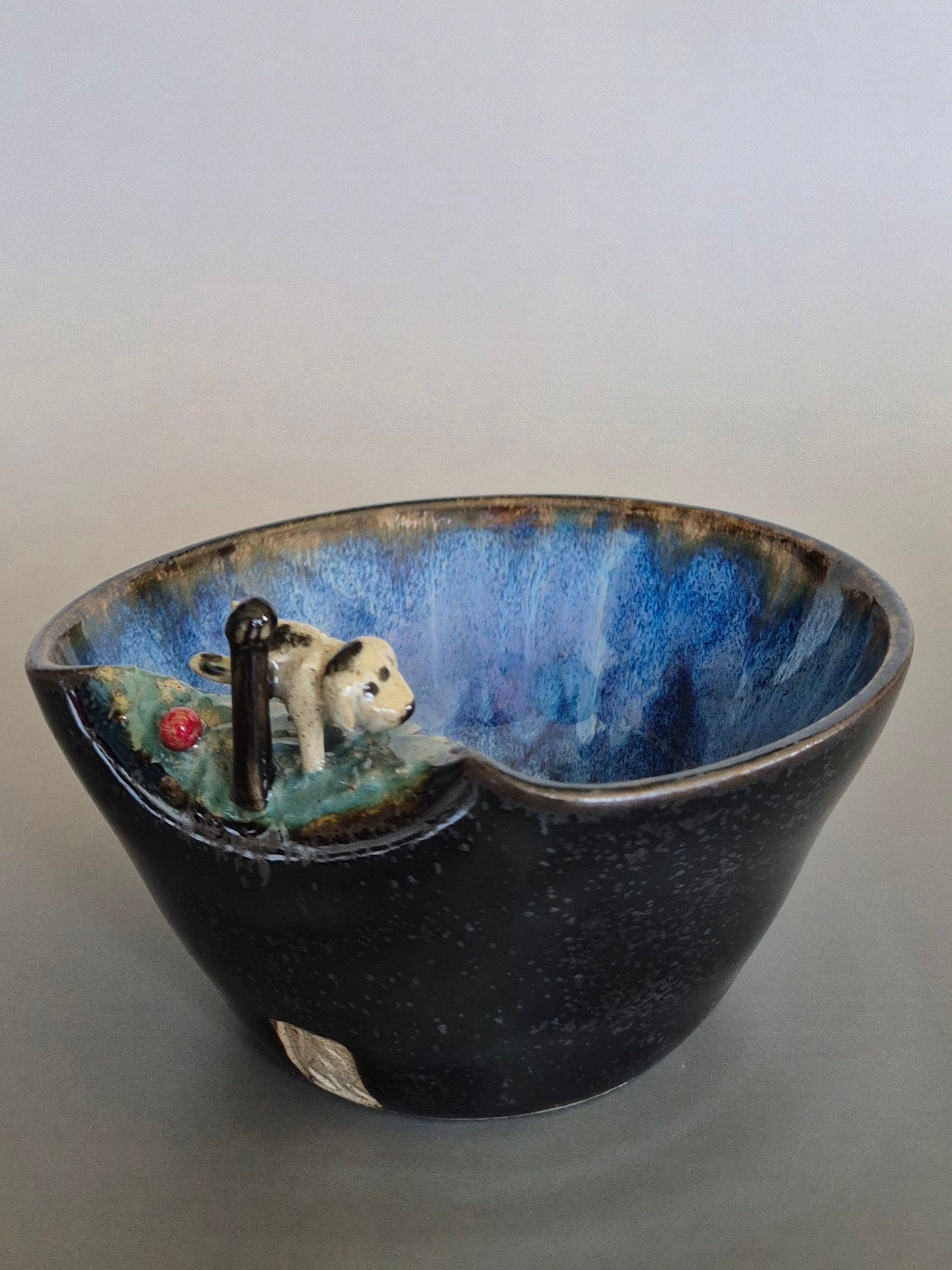 Ceramic bowl with a miniature scene of a dog by a pond on a plain background