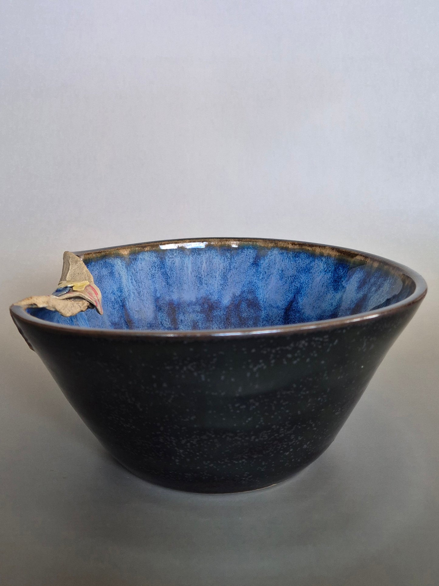 A ceramic bowl featuring sculptural details creating a miniature beach scene. On a plain background