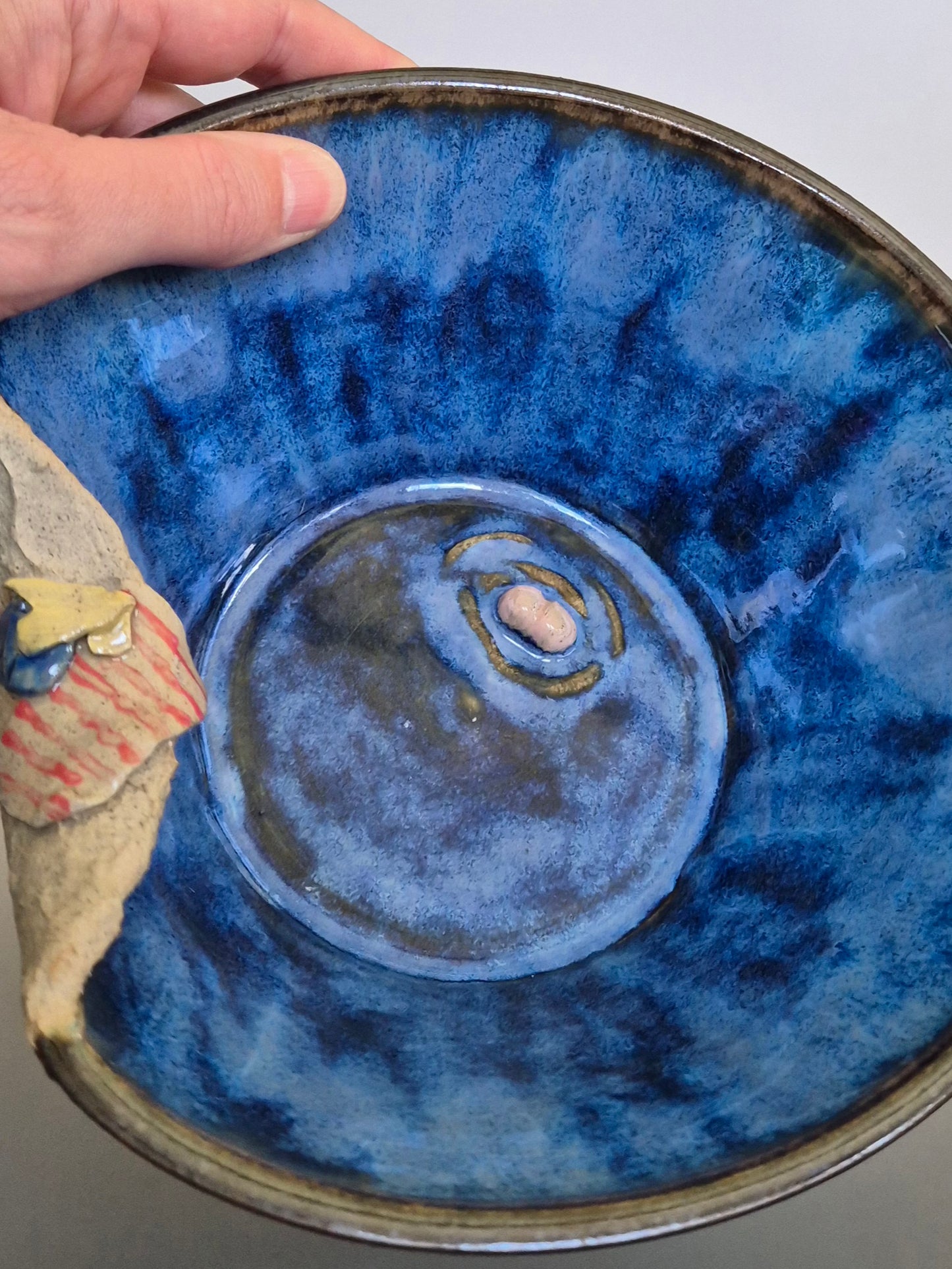 A ceramic bowl featuring sculptural details creating a miniature beach scene. On a plain background